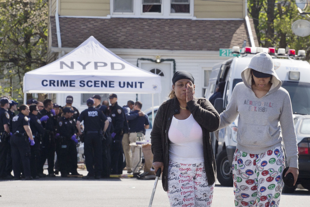 An unidentified woman wipes her face after talking with police officers Sunday about the shooting of a police officer in the Queens borough of New York.