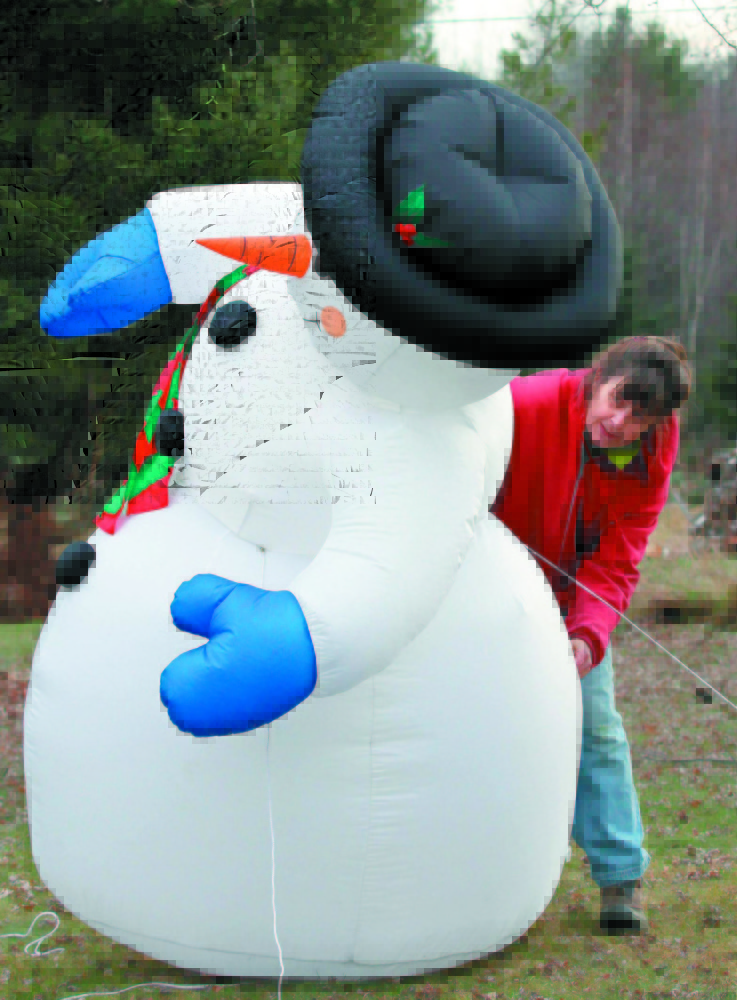 Tish Carr adjusts her inflatable snowman outside her home off Route 135 in Belgrade in this 2011 file photo.