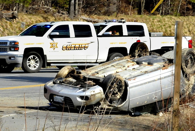 A firefighter walks past an overturned car Sunday on U.S. Route 201A in Norridgewock. The car’s lone occupant died Sunday afternoon after the car hit an embankment and overturned twice at the Ward Hill Road intersection.