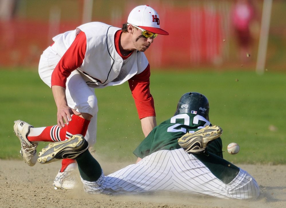 Winthrop High School’s Antonio Meucci dives into second base as Hall-Dale High School’s Tyler Dubois tries to make a play during a Mountain Valley Conference game Monday in Farmingdale.
