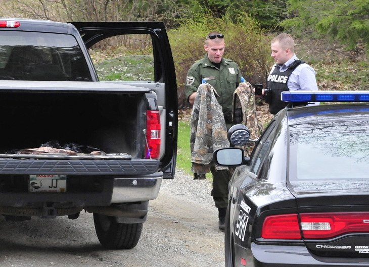 Game warden David Ross, left, and Winslow Detective Ron McGowen look over turkey hunting gear, including back packs and two shotguns, from a truck in Winslow on Tuesday. A man was taken to MaineGeneral Medical Center in Augusta with injuries to the face following a hunting accident with his wife.