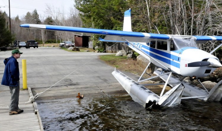 Plane owner Kenneth Comfort of Pittsfield looks over his heavily damaged 1965 Cessna 180 float plane at the Hartland town landing on Great Moose Lake on Tuesday.
