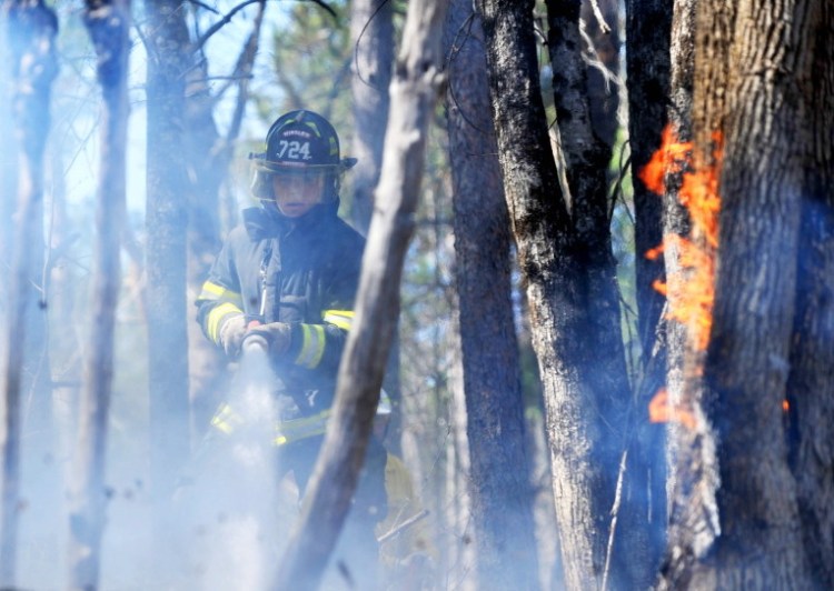 Jonathan Berringer, a firefighter with the Winslow fire department, battles a grass fire on Morrill Road in Winslow on Tuesday.