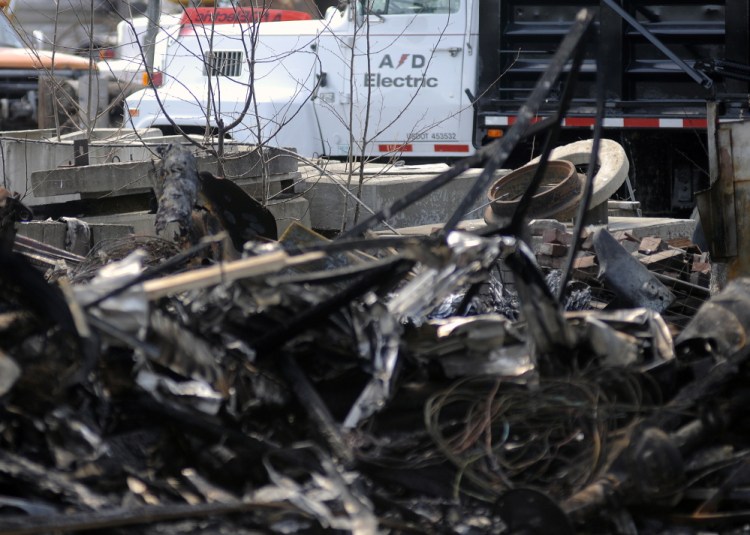 The AD Electric site in Monmouth on Wednesday consisted of charred vehicles and a burned building. The Office of the State Fire Marshal and the Maine Department of Environmental Protection are investigating Tuesday’s fire.