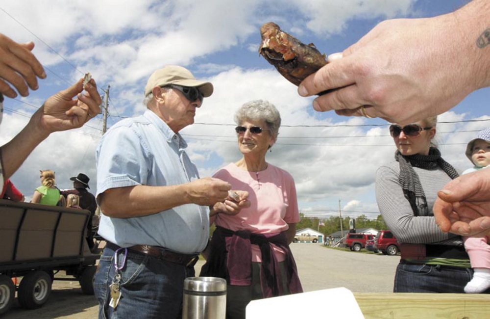 Erma Blakney, of Fairfield, center, looks over as her friend, Edward Fisher, tastes a smoked alewife during the 2013 Benton Alewife Festival. Smoked alewives are on the menu for Eating with the Alewives, a community dinner that kicks off the annual festival on Friday night.