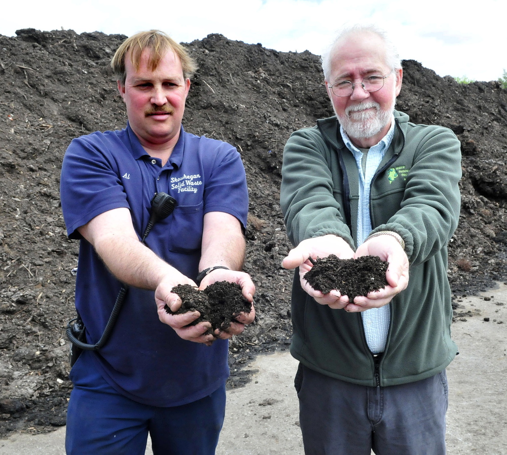Al White, left, and Randy Gray hold handfuls of rich compost from organic material processed at the Regional Recycling Center in Skowhegan on Wednesday.