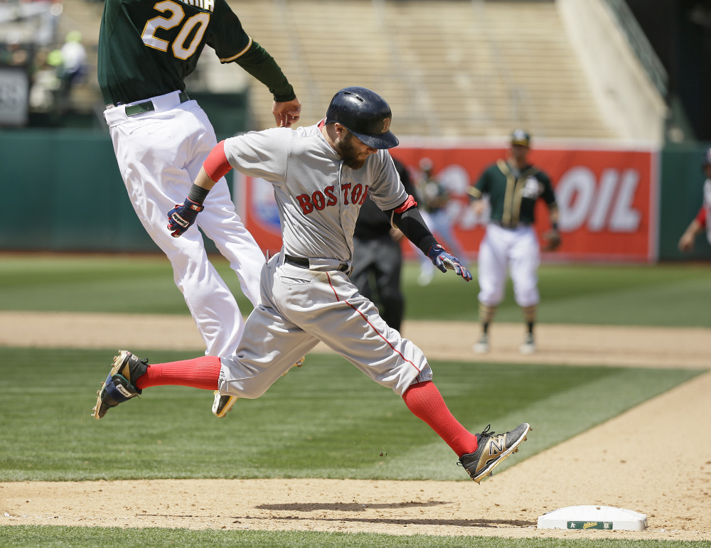 Boston Red Sox second baseman Dustin Pedroia runs safely to first base as Oakland Athletics first baseman Mark Canha leaps for the throw in the eighth inning Wednesday in Oakland, Calif. The Red Sox won 2-0.