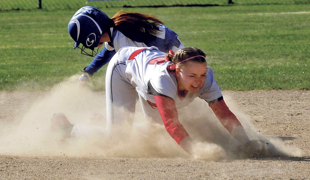 Hall-Dale’s Eva Shepard falls forward in dust trying to field throw as Madison’s Ashley Emery makes it to second base Thursday in Madison.