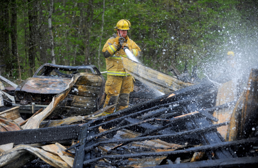 Kyle King with the Burnham fire department mops up a garage fire on Webb Road in Pittsfield on Saturday. Firefighters were dispatched around 1:30 in the afternoon. The garage was a total loss.(