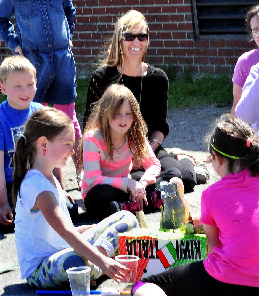 Athens Community School teacher Amy Bown watches on Thursday as students Sydney Sillanpaa, left, and Lily Cooley demonstrate a simulated volcano eruption.