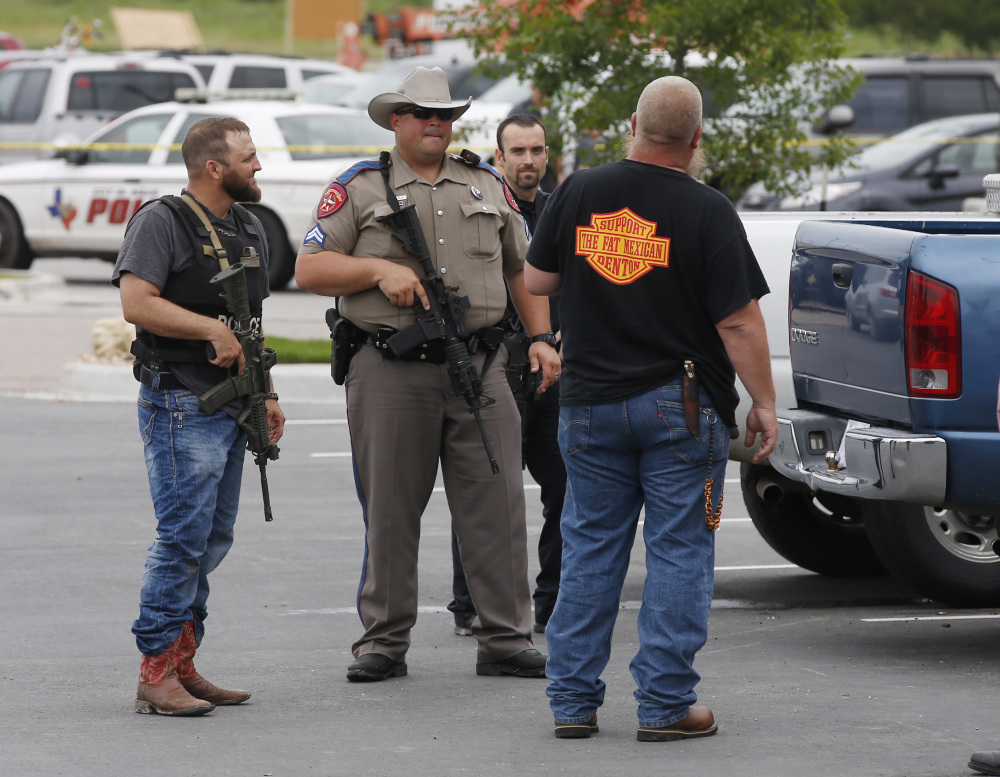 Law enforcement officers talk to a man near the parking lot of a Twin Peaks Restaurant Sunday in Waco, Texas, after a shooting involving rival biker gangs.