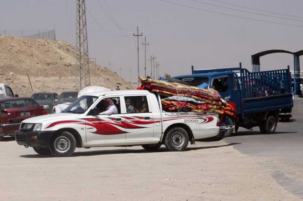 In this Monday, photo, civilians fleeing their hometown of Ramadi, Iraq, pull over their pickup truck at a police checkpoint as they drive through Habaniyah town, 80 kilometers (50 miles) west of Baghdad.