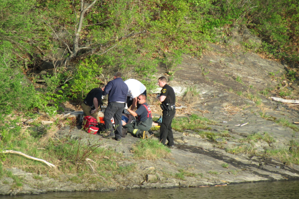 Emergency workers help a reportedly unresponsive man on the bank of the Kennebec River in Winslow on Tuesday evening.