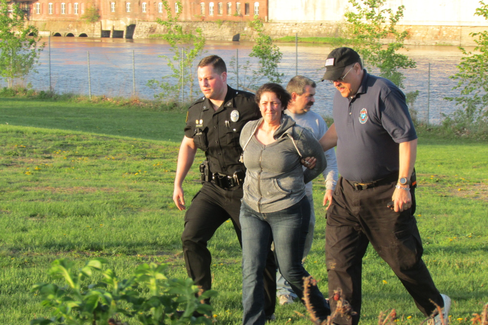A woman is taken into custody by Winslow Police Officer Alex Jones and Waterville Fire Chief David LaFountain near the Two Cent Bridge in Waterville Tuesday evening.