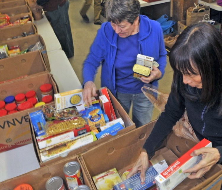Eleanor Kidwell, left, and Alyssa Wingate sort donated food on earlier this month at the Augusta Food Bank.