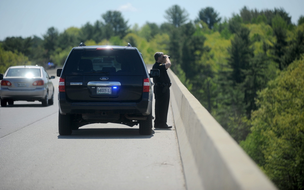 Winslow police officer Shawn O’Leary looks for a possible jumper off Carter Memorial Bridge on Friday.