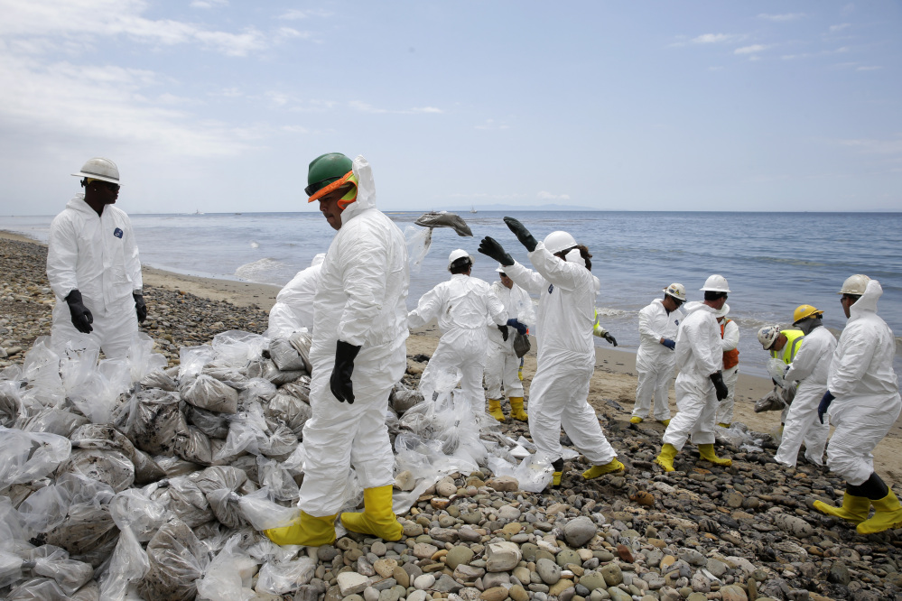 Clean up workers gather oil-contaminated sand bags at Refugio State Beach, north of Goleta, Calif.
