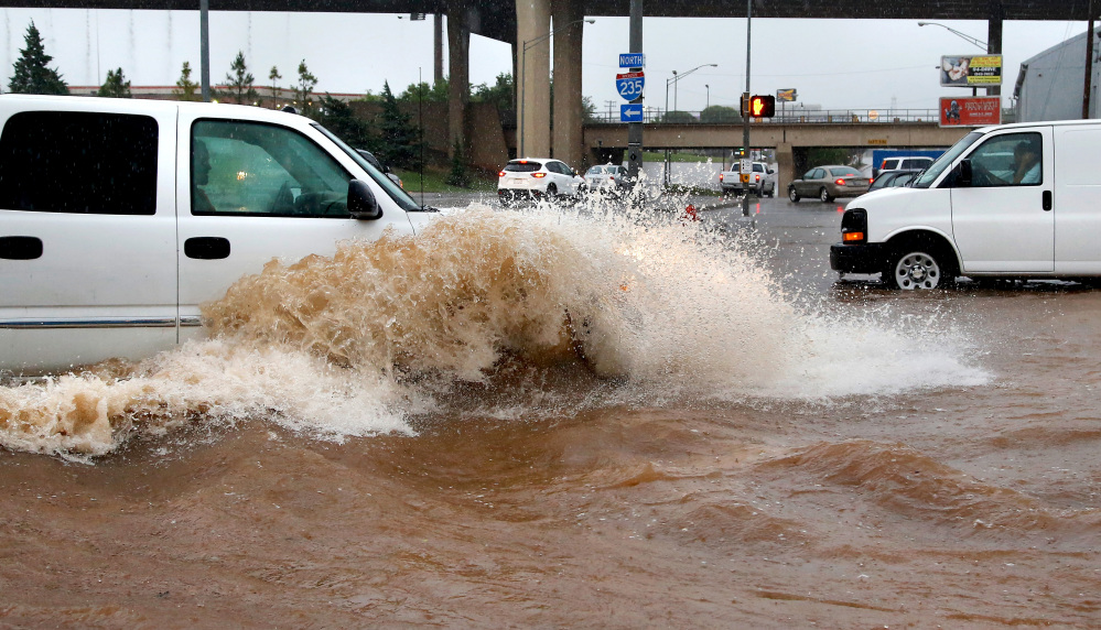 A truck creates a wave as it forces its way through high water Saturday, in Oklahoma City.