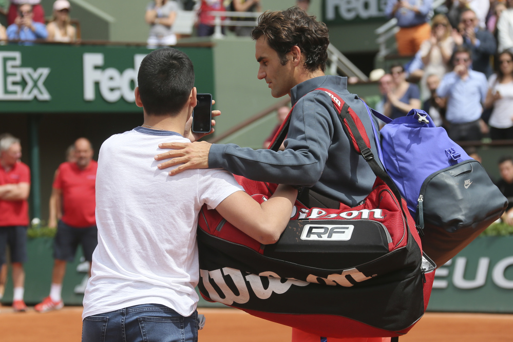 A boy who climbed down from the stands takes a selfie with Roger Federer on Sunday in the first round match of the French Open against Colombia’s Alejandro Falla at the Roland Garros stadium, in Paris, France.
