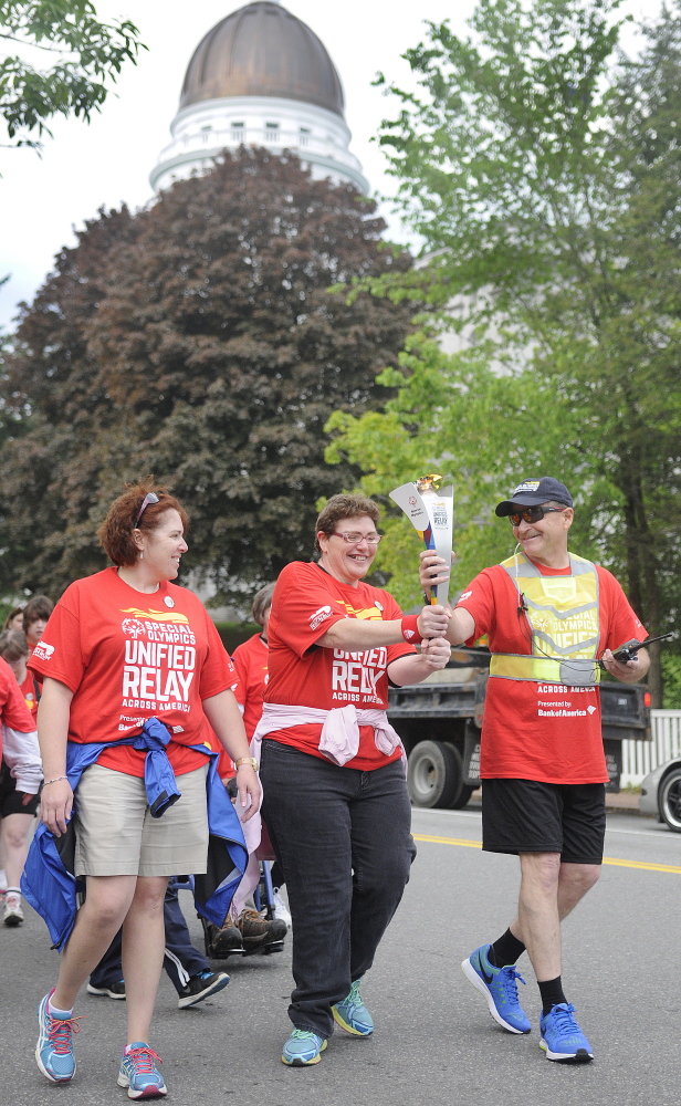 The torch is carried past the State House in Augusta on Tuesday on the first leg of the Law Enforcement Torch Run to raise funds for the Special Olympics.