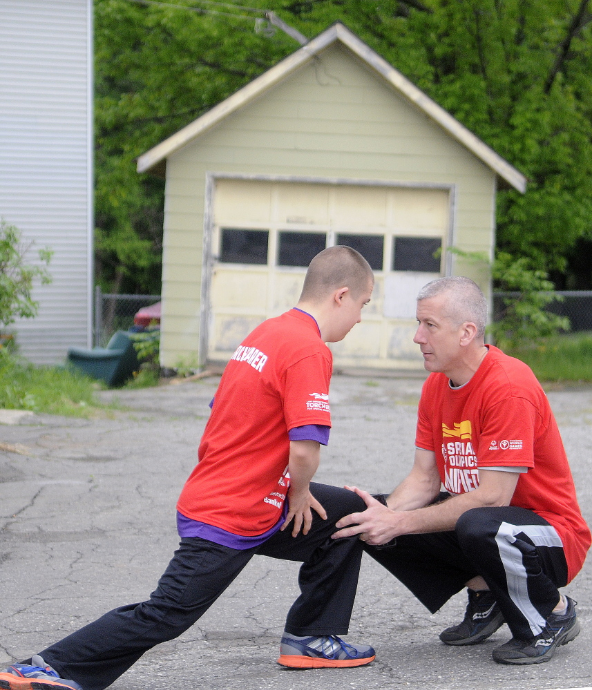 Special Olympian Zach Ewing stretches with his father, Orono Police Chief Josh Ewing, before running on the first leg of the Law Enforcement Torch Run in Augusta on Tuesday to raise funds for Special Olympics.