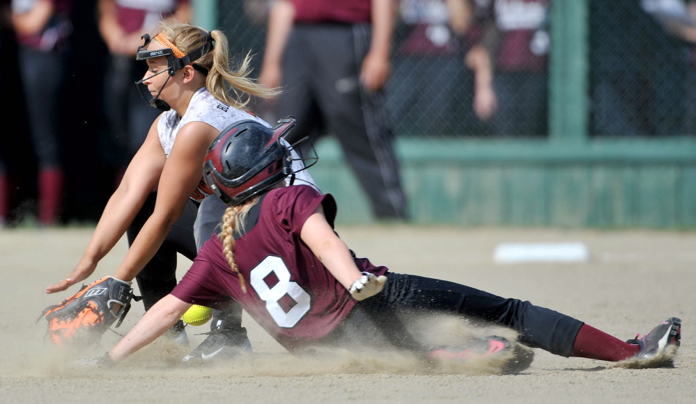 Winslow shortstop Liz Pullen, back, tries to field a throw as Nokomis baserunner Audrey Temple (8) slides safely into second base in the first inning of a Kennebec Valley Athletic Conference Class B game Wednesday in Winslow. The Warriors won 4-1 in eight innings.