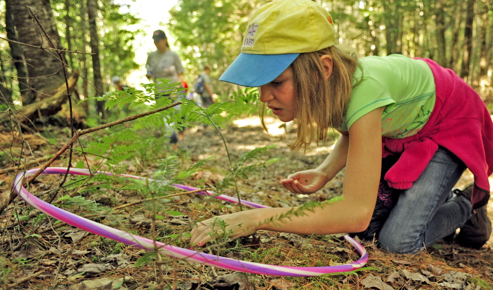 During the “map your kingdom” exercise, Molly Anderson searches for what’s inside the small circle of forest floor ringed by a hula hoop Friday during Forestry Day in the town forest around China’s primary and middle schools. She and fellow student Kiera Grady then drew a map of what they found.