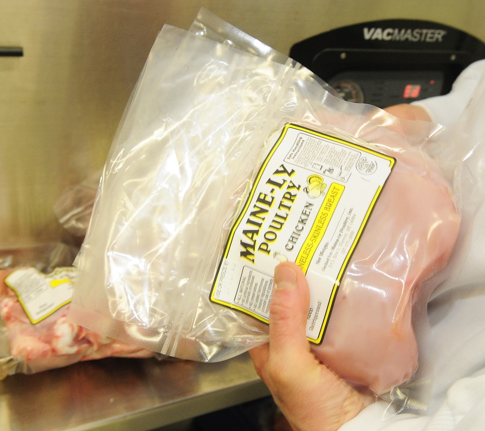 Co-owner and manager Gina Simmons takes chicken breasts out of a vacuum sealer March 5 at Common Wealth Poultry Co. in Gardiner.