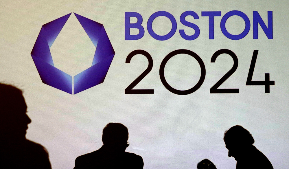 In this Jan. 21, 2015 file photo, shadows of organizers and reporters pass a video display screen prior to a news conference by organizers of Boston’s campaign for the 2024 Summer Olympics in Boston.