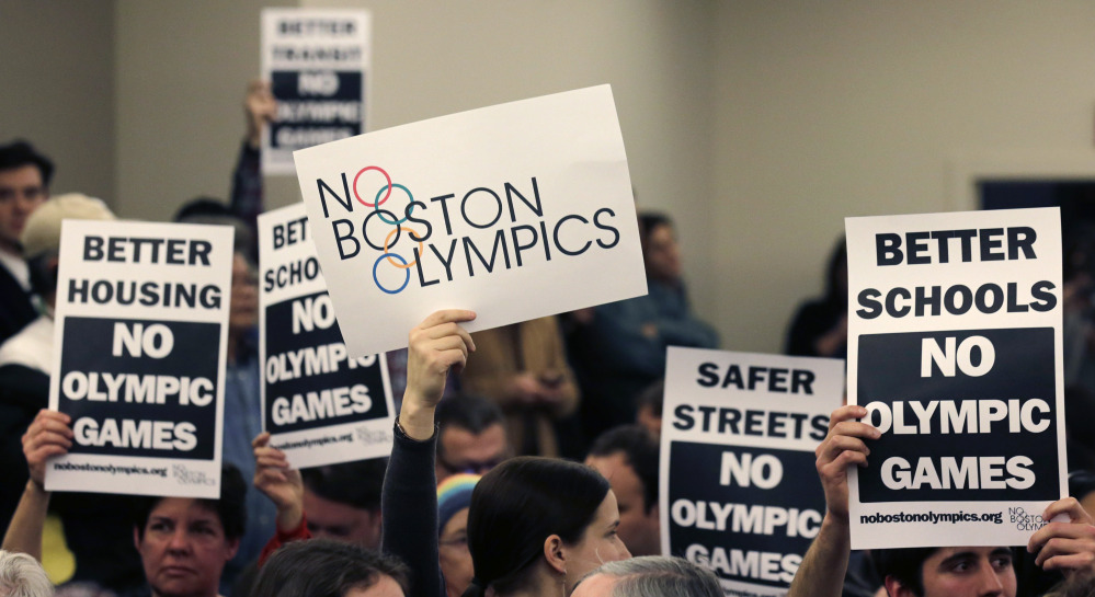 In this Feb. 5, 2015 file photo, members of the audience hold up placards against the Olympic Games coming to Boston, during the first public forum regarding the Boston 2024 Olympic bid in Boston.