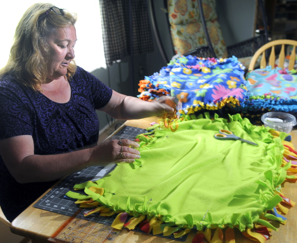 Judy Wildes works Sunday on a fleece quilt at her Augusta home. Wildes has donated more than 60 of the blankets for premature babies at Maine Medical Center in Portland after her grandson was born prematurely several months ago.