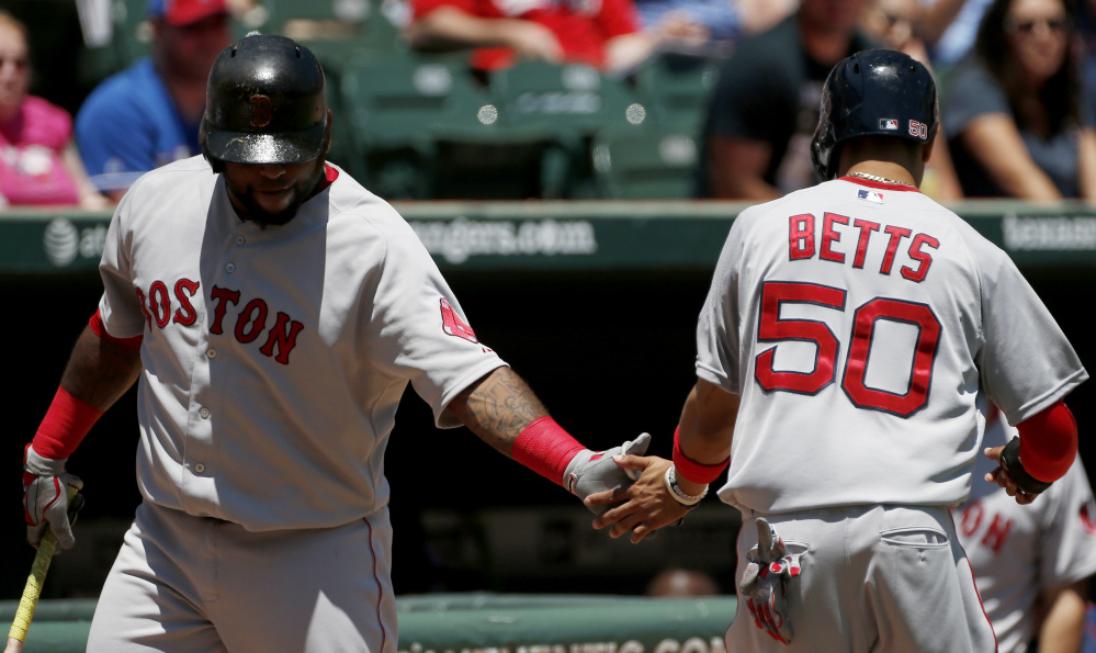 Boston Red Sox Mookie Betts is congratulated by Pablo Sandoval after scoring a run on an RBI single hit by Hanley Ramirez during the first inning Sunday against the Texas Rangers in Arlington, Texas. The Rangers won 4-3.