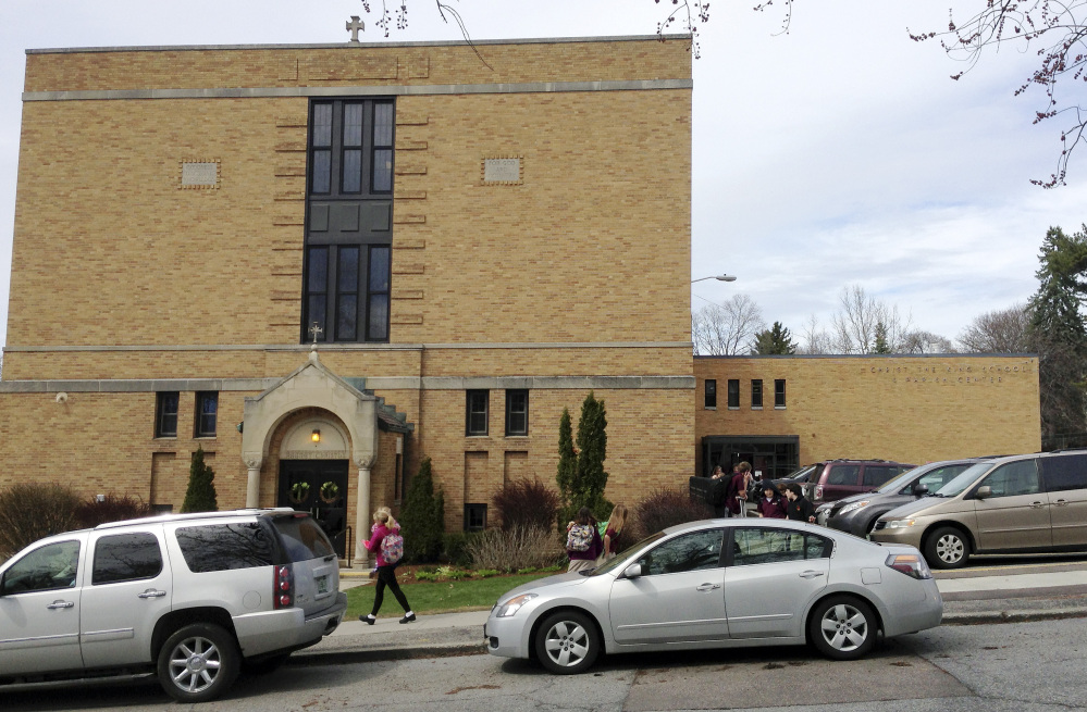Parents pick up their children at the end of the school day at Christ the King School in Burlington, Vt. The church’s sound system that plays recorded bells and hymns has struck a sour note with some neighbors, who find it noisy and intrusive.The Associated Press