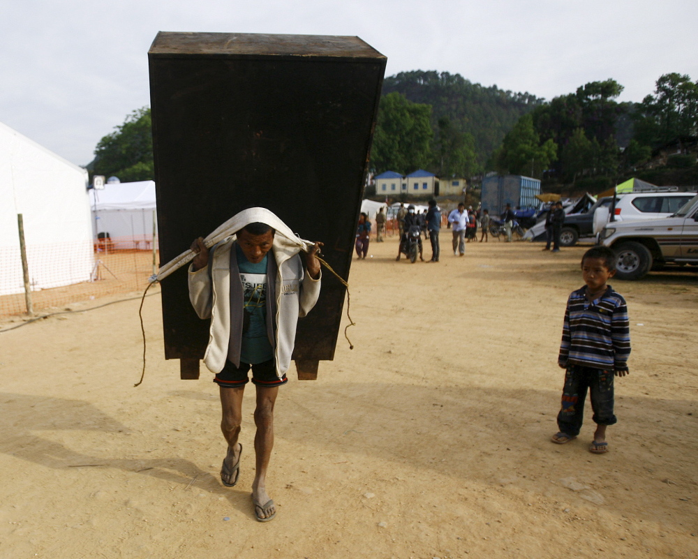 A man carries a cupboard after salvaging it from a collapsed house in Nepal on Tuesday. Dawn Habash, of Augusta, is still missing more than a week after the earthquake.