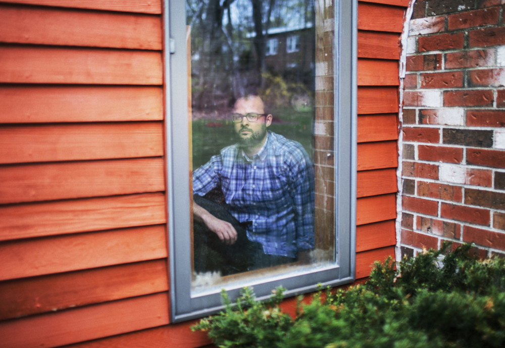 Matt Lauzon looks out from his childhood home in Biddeford. When he was a teen, he says, Biddeford police officer Stephen Dodd would park nearby and flash his lights to intimidate him and to remind him he was being watched.