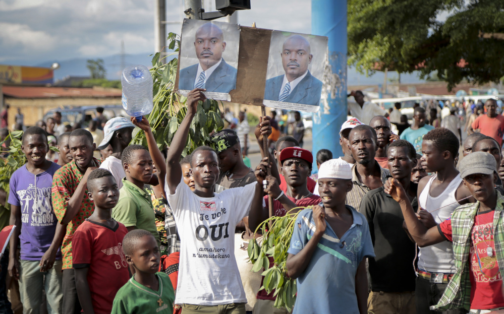Supporters of Burundian President Pierre Nkurunziza hold photographs of him as they turn out to watch the presidential motorcade arrive in the Kamenge district of the capital, Bujumbura, on Friday.