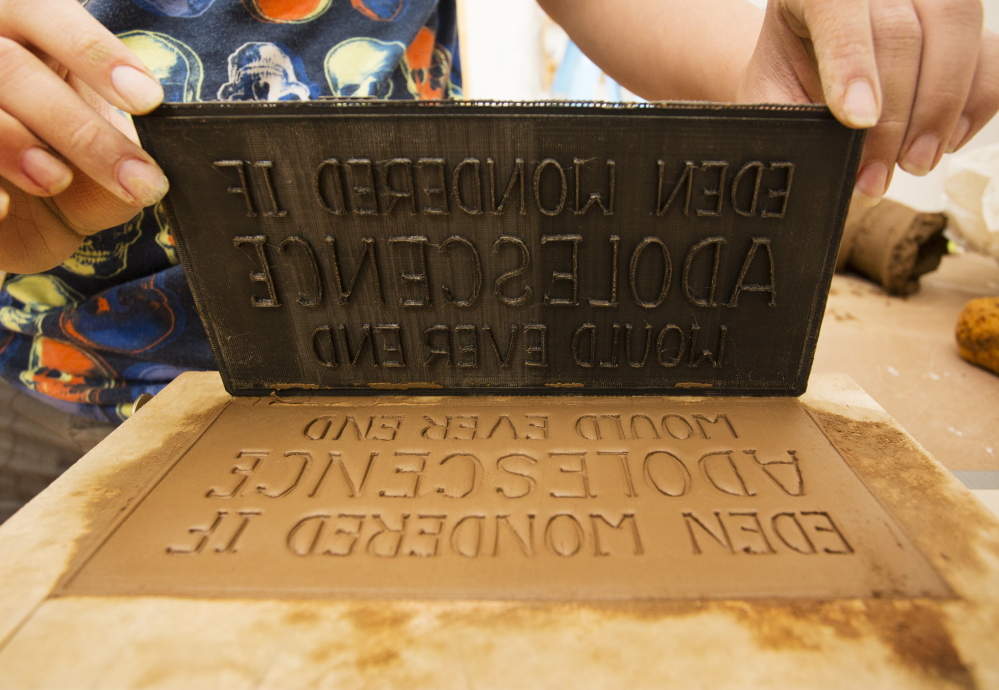 Artist Rochelle Garcia lifts a type mold after imbedding its impression into a brick created to tell stories about the India Street neighborhood and be installed, becoming a decorative part of the area.