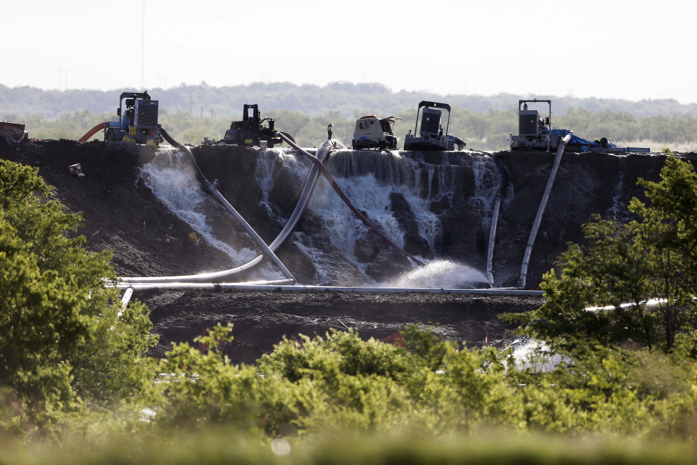 Workers attempt to relieve the pressure from the earthen dam at Padera Lake, Wednesday, in Midlothian, Texas.