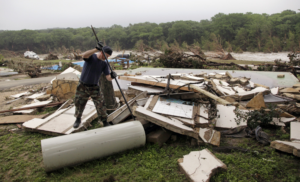 Kevin Calaway pries apart debris from a cabin shattered from a flood days earlier at a resort along the Blanco River, Tuesday, in Wimberley, Texas.