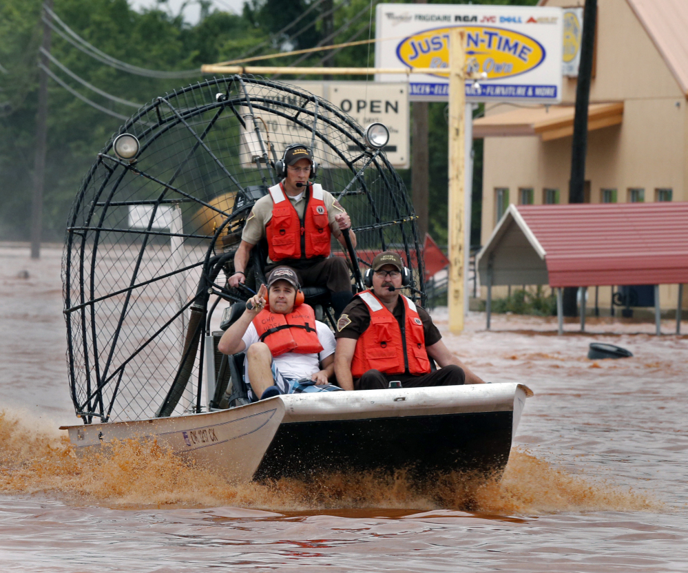 Highway patrolmen rescue Justin Nimmo, left, from his business, Just-In-Time, after flooding caused by rising water from Saturday night’s storms trapped him in the store on Sunday, May 24, 2015 in Purcell, Okla.