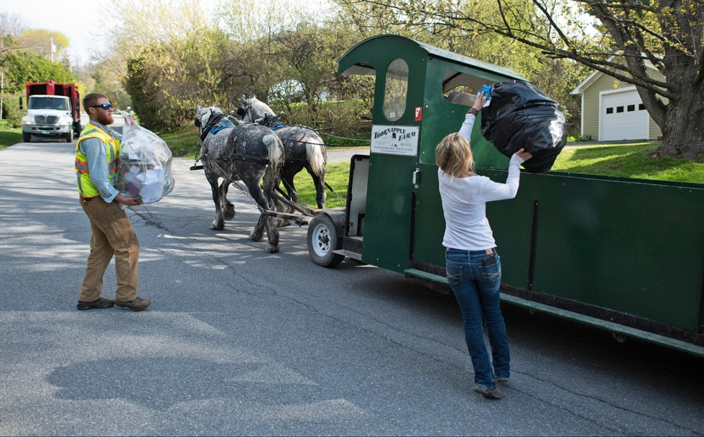 Nick Hammond, left, and Amanda Morse collect garbage and recycling in Middlebury, Vt. Patrick Palmer's horse-drawn garbage collection business has clip-clopped through the sleepy village of Bristol collecting trash for 18 years. Now he is training Hammond and Morse to collect trash with a team of draft horses in the busier college village of Middlebury. The Associated Press