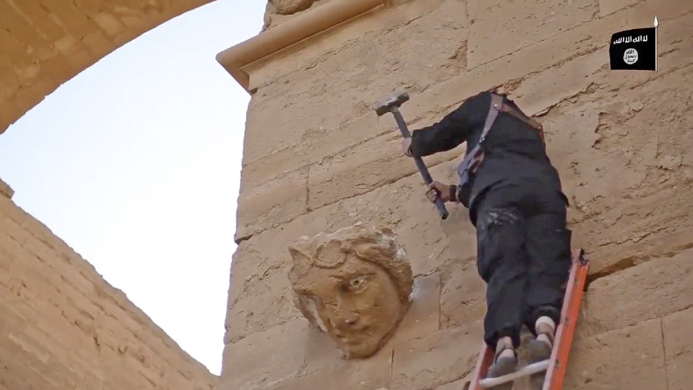 In this image from a militant video posted on YouTube on April 3, 2015, a militant hammers away at a face on a wall in Hatra, a large fortified city recognized as a UNESCO World Heritage site, 68 miles southwest of Mosul, Iraq. The Islamic State group’s attacks on these famed archaeological treasures are partially motivated by the group’s hostility to non-Islamic and pre-Islamic cultures. But some antiquities authorities have charged that the destruction is a partial cover for the militants’ lucrative business in selling looted artifacts on the black market. 