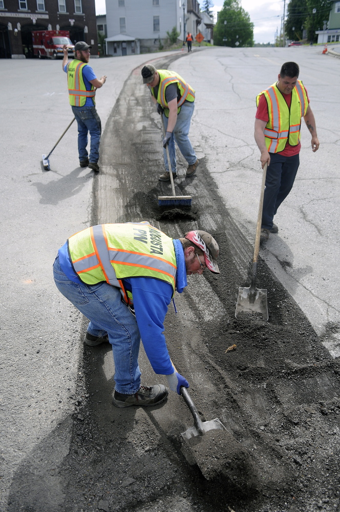 Augusta Public Works employees collect pavement chipped from the shoulder of Water Street in front of Hartford Fire Station in Augusta in this May 20 file photo. Paving in that area is scheduled for Wednesday and Thursday.