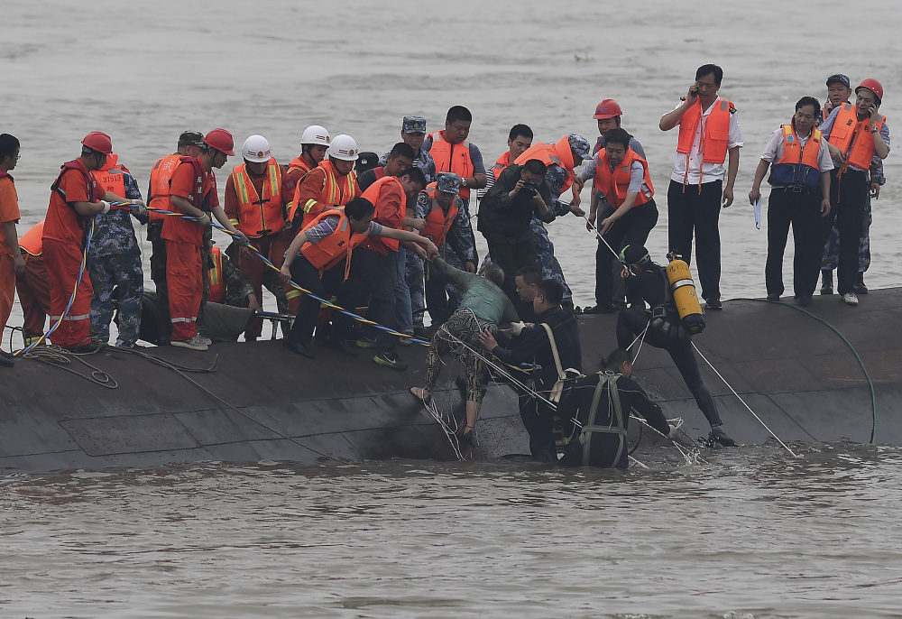 In this photo released by China’s Xinhua News Agency, rescuers save a survivor, center, from the overturned passenger ship in the Jianli section of the Yangtze River in central China’s Hubei Province Tuesday.