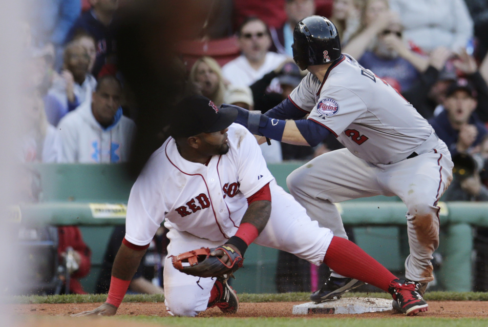 Boston Red Sox third baseman Pablo Sandoval drops to a knee after mishandling a throw from catcher Blake Swihart, which allowed Minnesota Twins’ Brian Dozier, right, to score, breaking a 4-4 tie during the ninth inning Thursday in Boston. The Twins defeated the Red Sox 8-4.