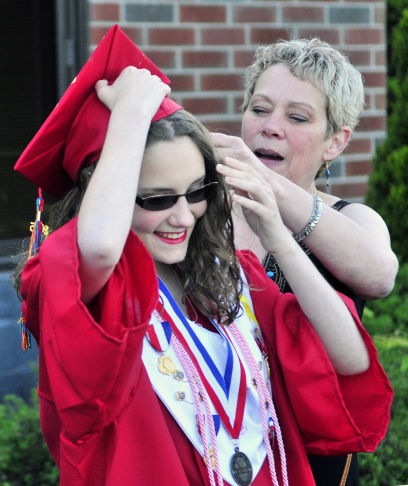 Graduate Tesla Newell, left, gets help from her mother, Terri Newell, while adjusting her hair and her mortarboard Thursday before Messalonskee High School’s graduation at the Augusta Civic Center.