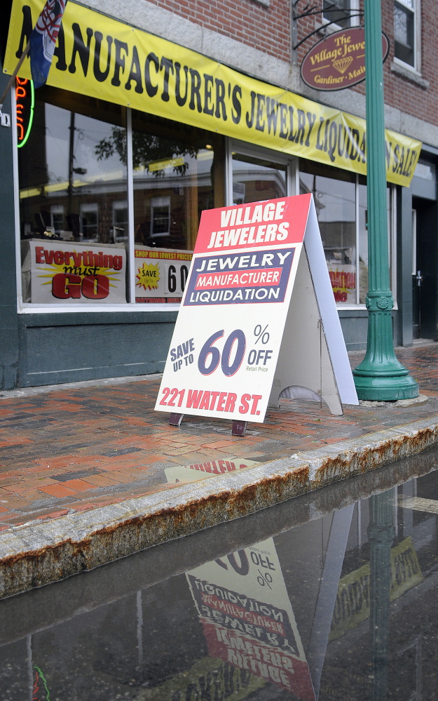 Daniel Lane displays a sign for a discount sale at The Village Jeweler store on the street in front of his business in Gardiner. State officials have told him to stop using sign walkers to advertise a liquidation sale.