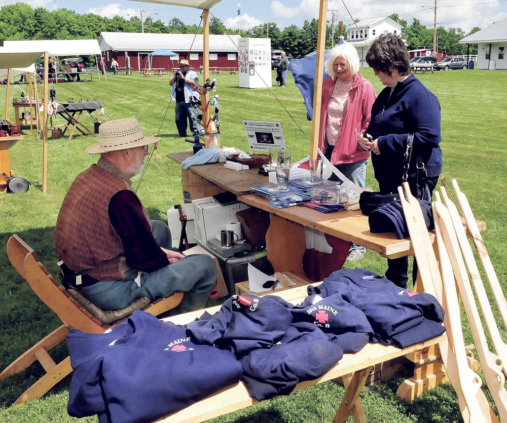 Gary Moore speaks with Sue McLaughlin, center, and Jill Low at a Civil War store set up Saturday during a war re-enactment event in Clinton.