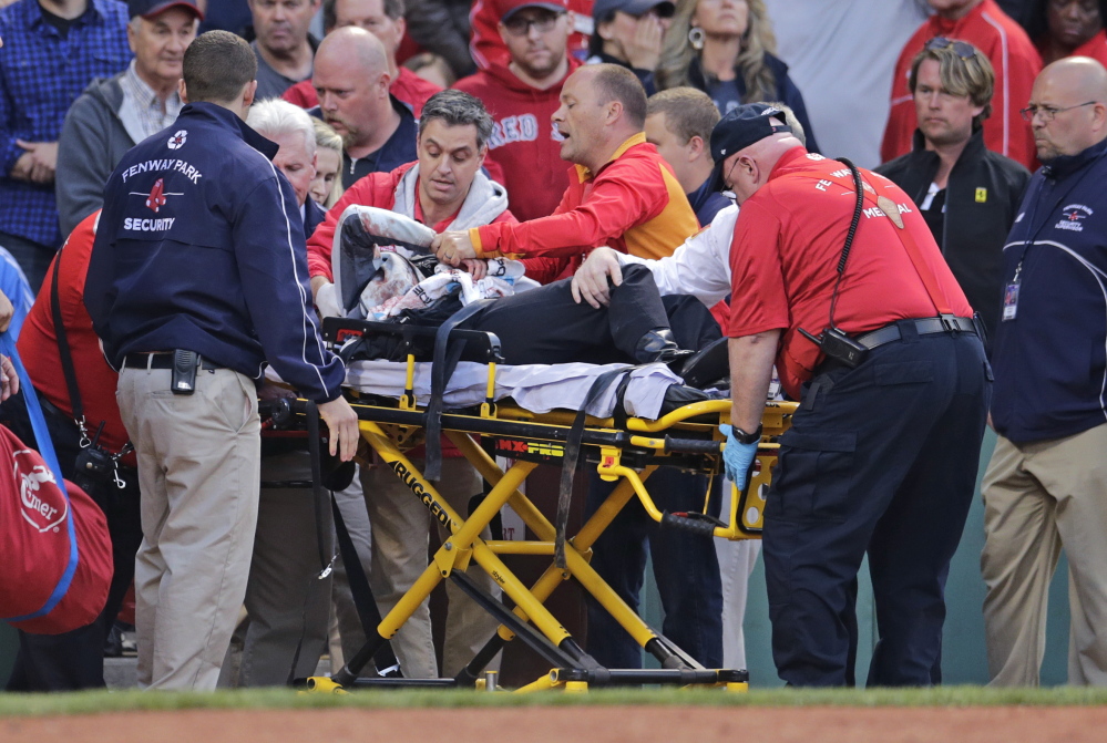 Tonya Carpenter, who was accidentally hit in the head with a broken bat by Oakland’s Brett Lawrie, is helped from the stands during a game against the Boston Red Sox on Friday at Fenway Park in Boston. The game was stopped while they wheeled her down the first base line.