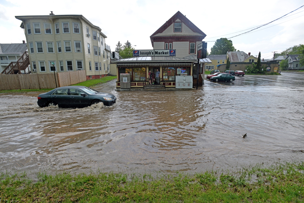 A car drives on flooded Front Street May 28 as heavy rain moved through Waterville. Two downtown businesses are still repairing damage from flooding in their building from the storm.